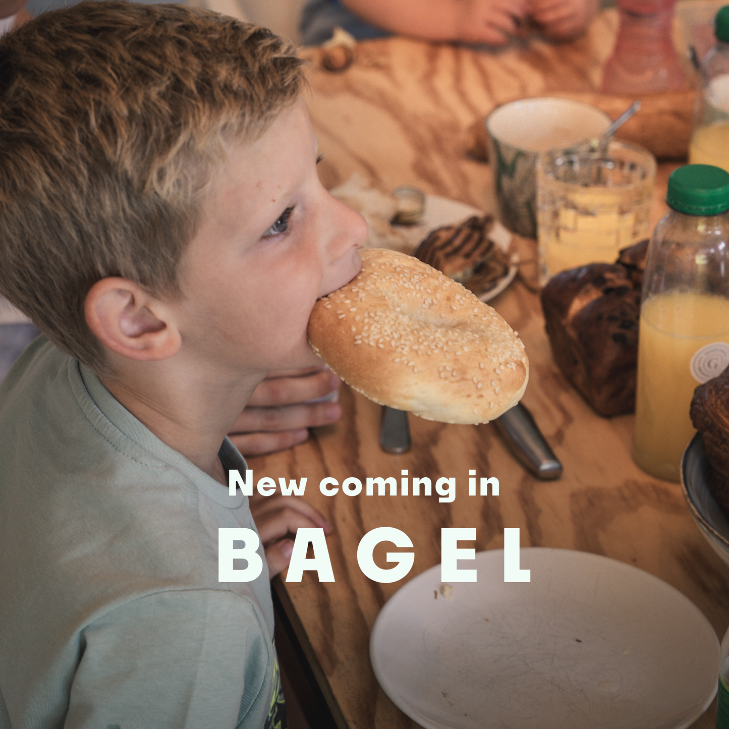 A boy eating a freshly baked New York style bagel on a breakfast table with only Gérard products.