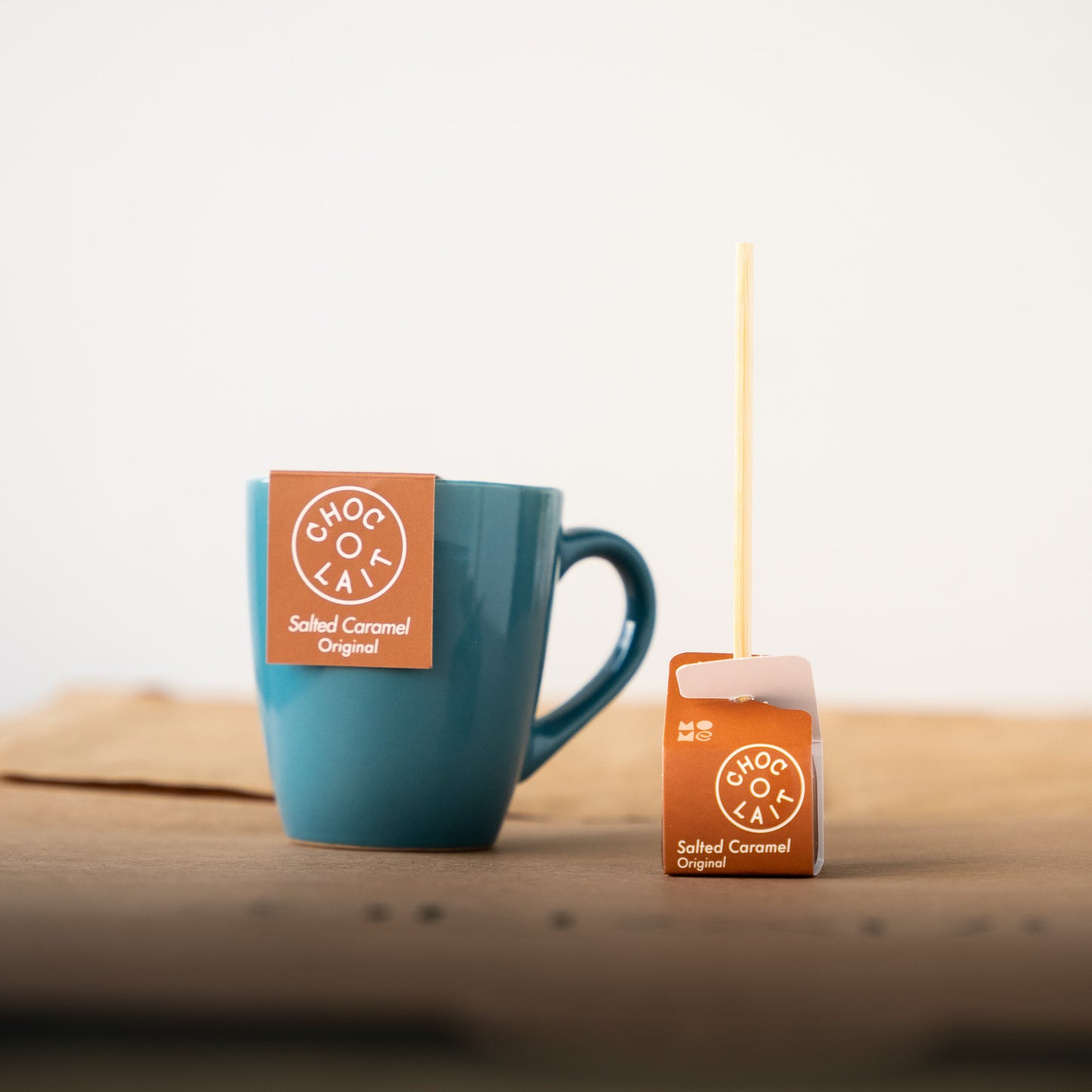 Choc-o-lait salted caramel stick displayed with a blue mug, offering a rich blend of milk chocolate and salted caramel for a luxurious hot chocolate experience.