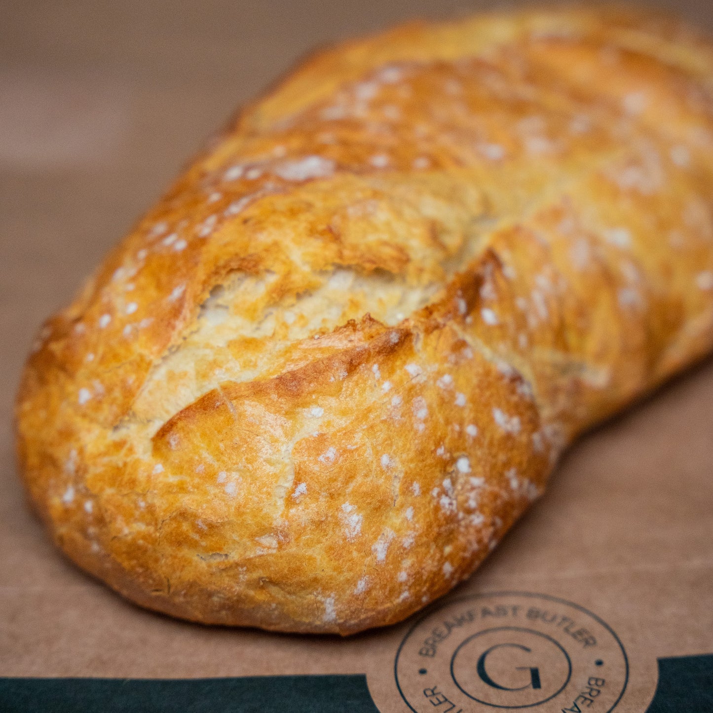 Whole loaf of white sourdough bread, baked to perfection with a thin, crispy crust