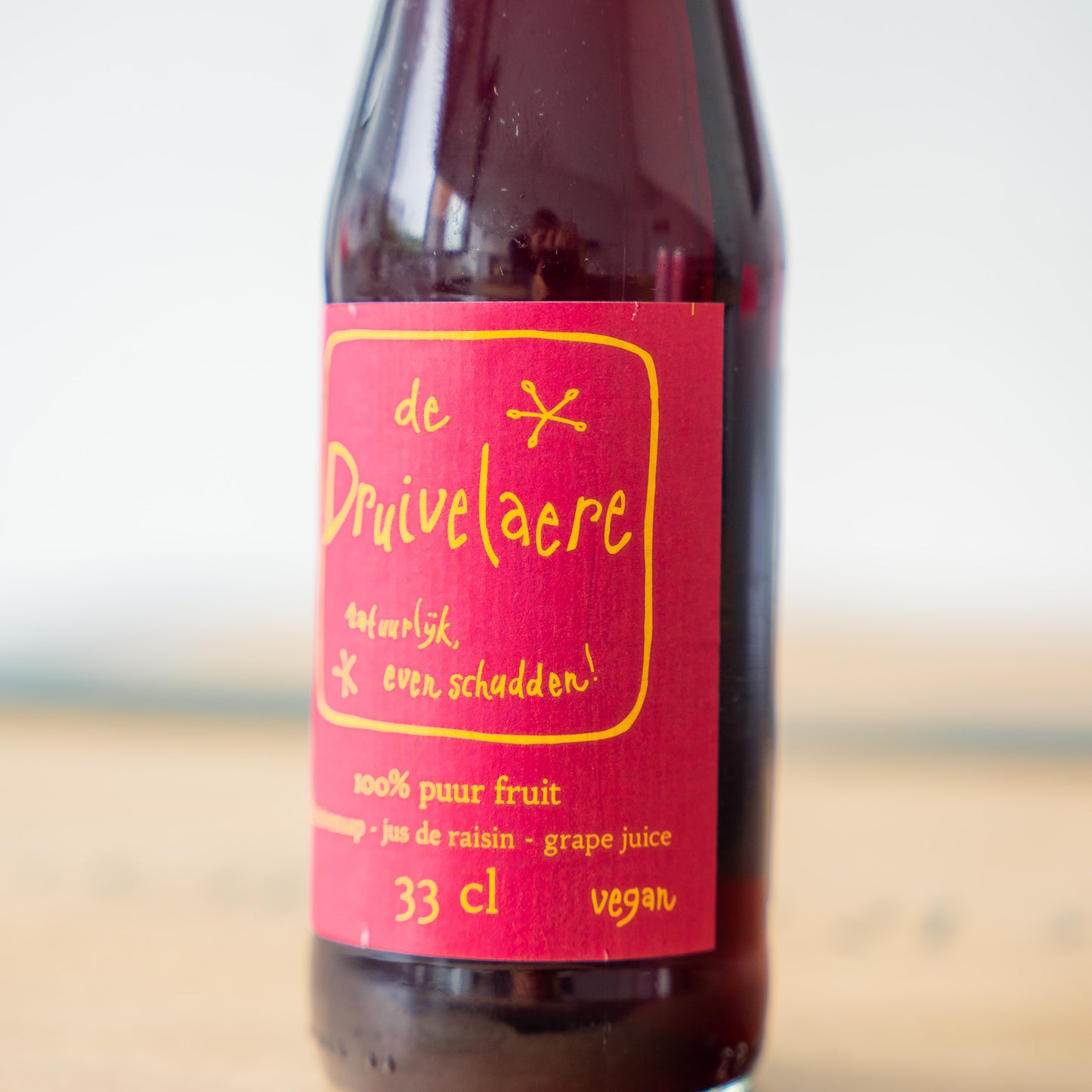 Close-up from Druivelaere grape juice bottle with a vibrant red and gold label, filled with 100% pure grape juice for a fruity and refreshing taste