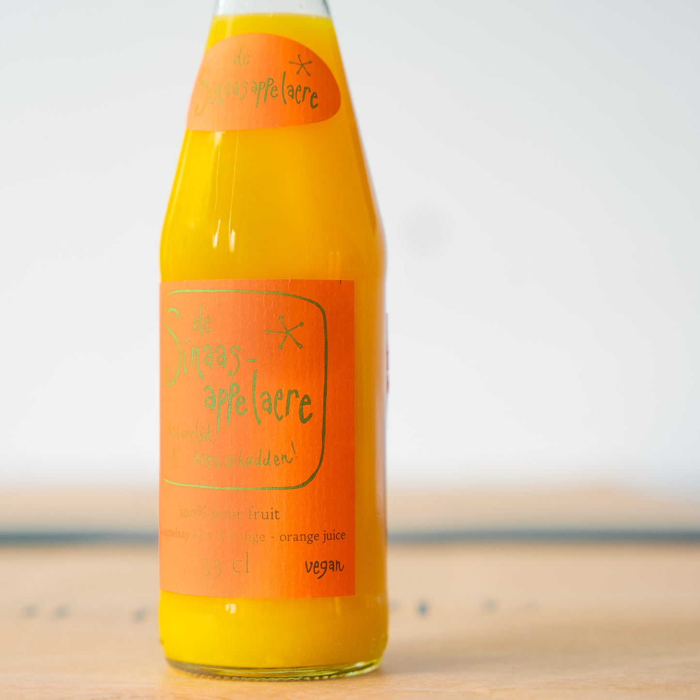 Close-up of Sinaasappelaere orange juice bottle with a bright orange label, filled with pure, unfiltered orange juice for a fresh and rich flavor