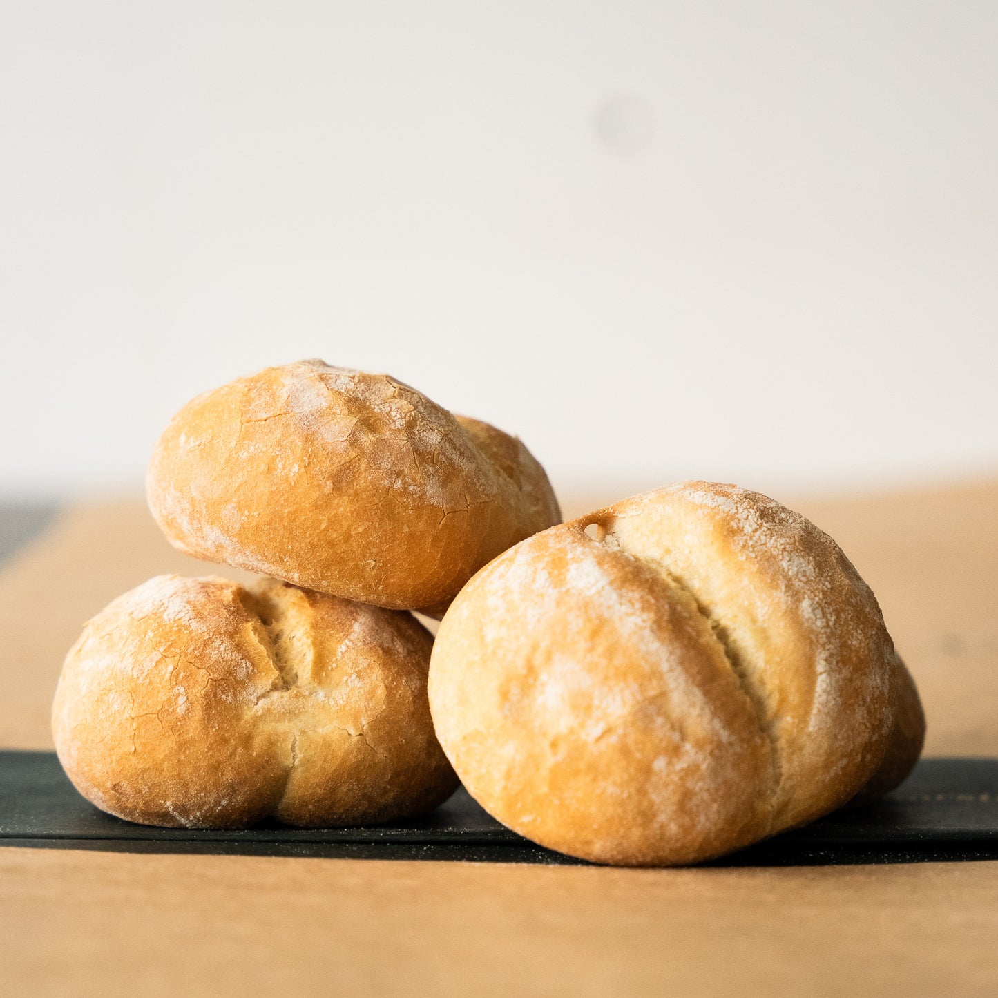 Three freshly baked pistolets on a wooden surface, showcasing their light and airy texture, a traditional Belgian favorite.