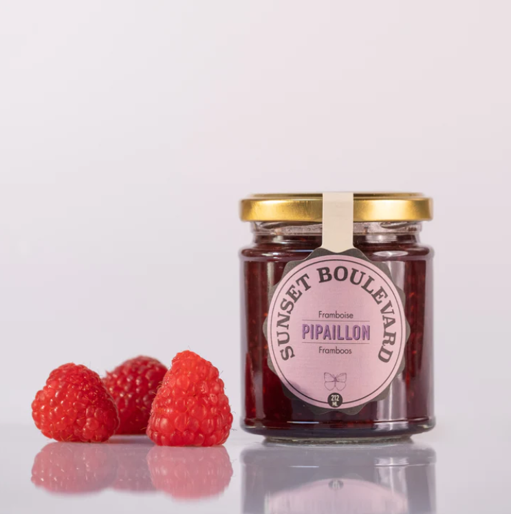 Raspberries laying next to a rasberry jam pot from Pipaillon.