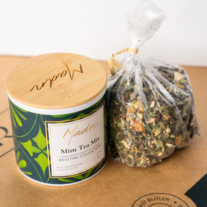 Madn Mint Tea Mix from the Restore Collection, featuring a stylish tin with a bamboo lid and a bag of loose-leaf tea, highlighting its premium quality and refreshing flavor