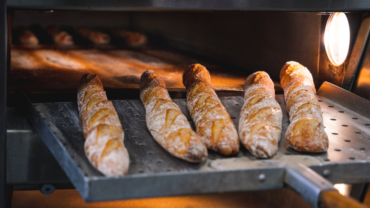 Artisanal bread and baguettes coming out of the Gérard Bakery oven