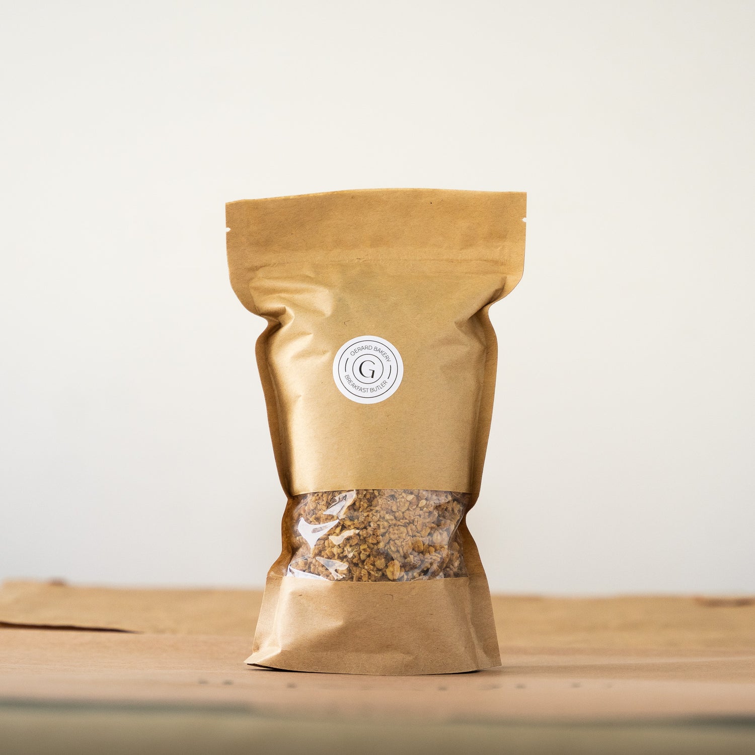 Brown paper bag of homemade granola mix with a transparent window showing the granola.