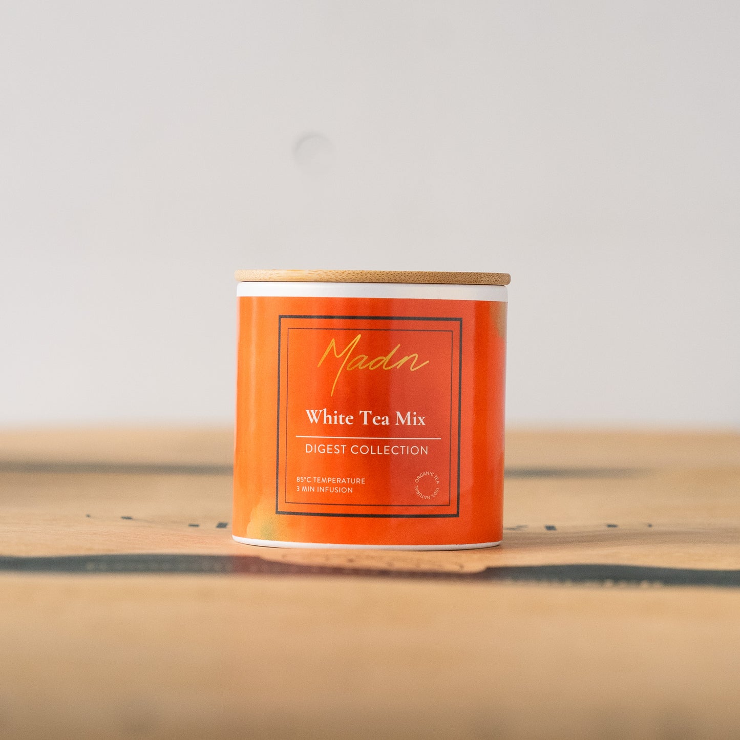 Madn White Tea Mix from the Digest Collection in a vibrant orange tin with a bamboo lid, offering a light and soothing tea blend for digestion support