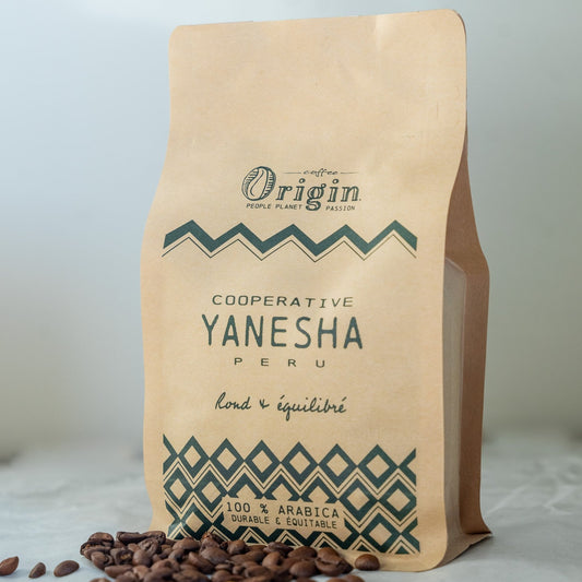 Coffee beans sourced from cooperative Yanesha in Peru into a Origin Coffee packaging with some beans laying around.