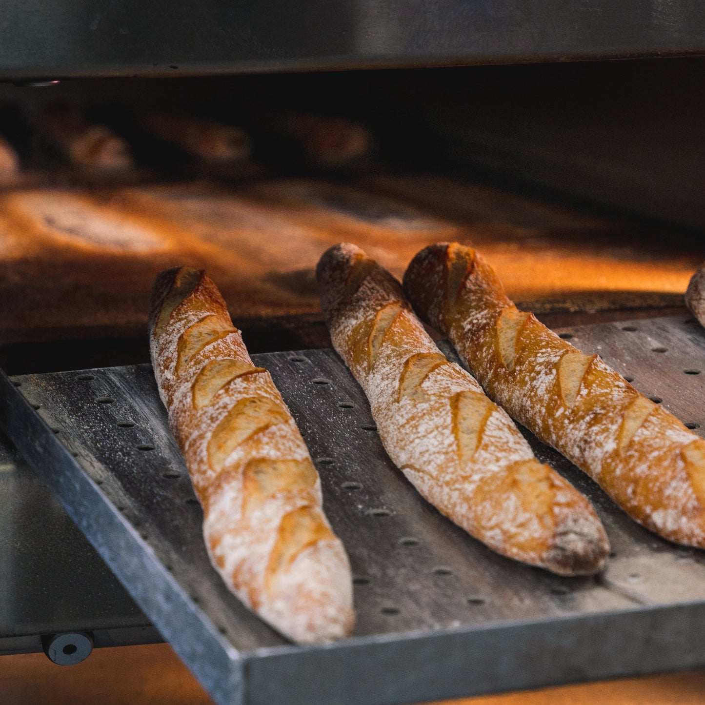 Three Gérard baguettes baked to perfection inside a hot oven, filling the air with a delightful scent.