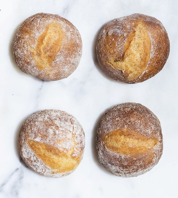 Four perfect Gérard sourdough pistoléts next to each other on a marmer kitchen table.